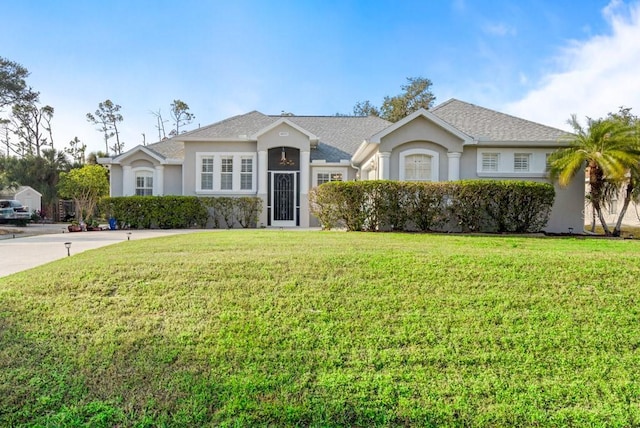 ranch-style home with a front yard, stucco siding, and a shingled roof
