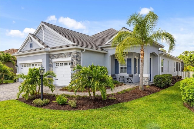 view of front of home with a porch, a garage, and a front lawn