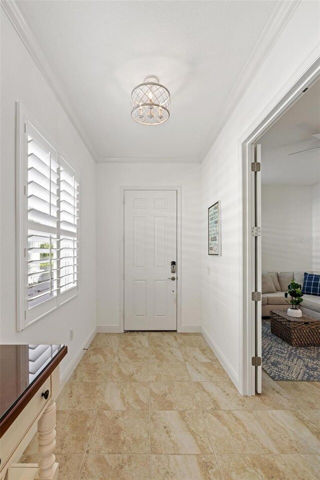 foyer with crown molding and an inviting chandelier