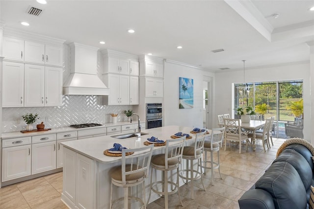 kitchen with appliances with stainless steel finishes, white cabinetry, custom exhaust hood, and sink