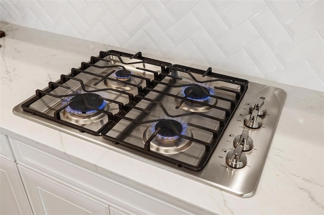 interior details featuring stainless steel gas stovetop, white cabinetry, and tasteful backsplash