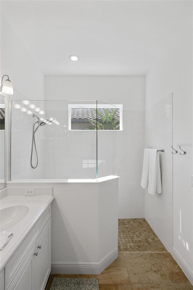 bathroom with a tile shower and vanity