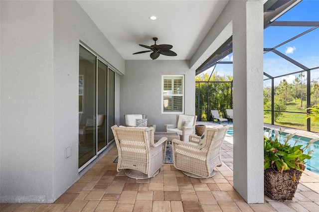 view of patio featuring ceiling fan, an outdoor hangout area, and glass enclosure