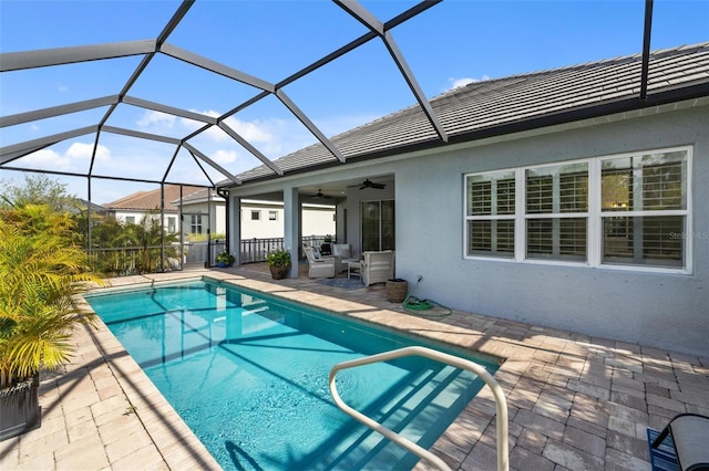 view of swimming pool with glass enclosure, ceiling fan, and a patio area