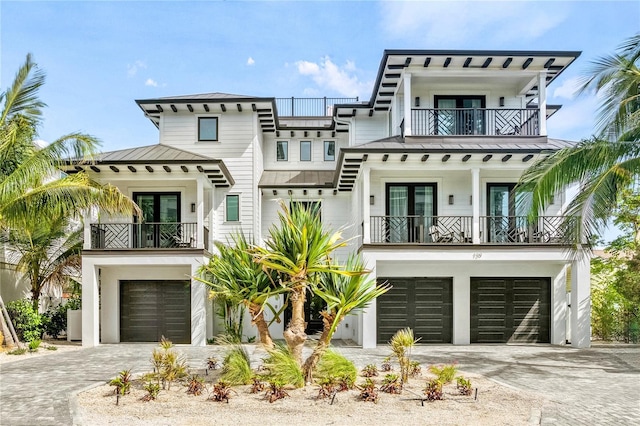 raised beach house featuring french doors, a balcony, and a garage