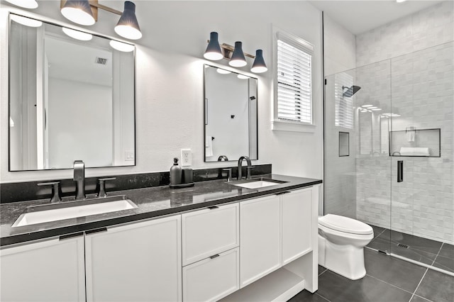 bathroom featuring tile patterned floors, vanity, a shower with shower door, and toilet