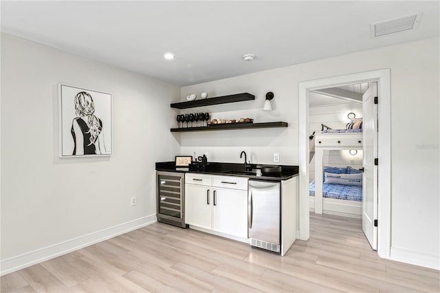 bar featuring wine cooler, white cabinetry, sink, and light wood-type flooring