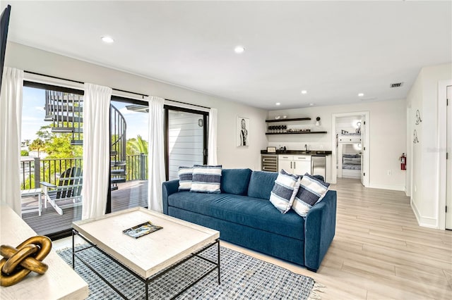 living room featuring light wood-type flooring, wine cooler, and indoor wet bar