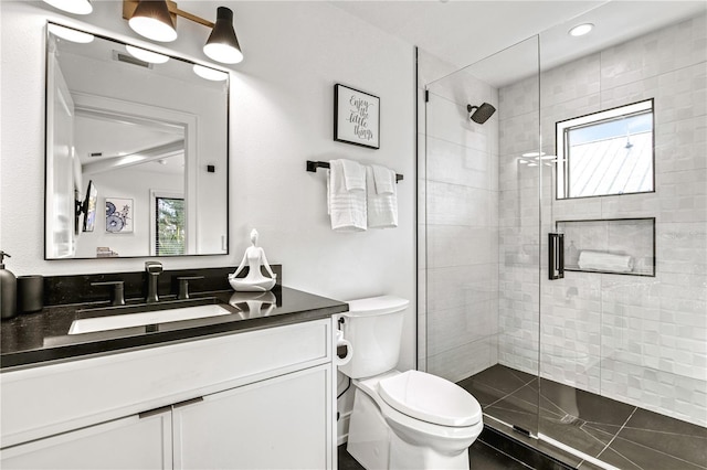 bathroom featuring a shower with door, vanity, a healthy amount of sunlight, and toilet