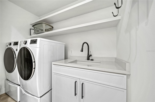 laundry room featuring cabinets, independent washer and dryer, light hardwood / wood-style flooring, and sink