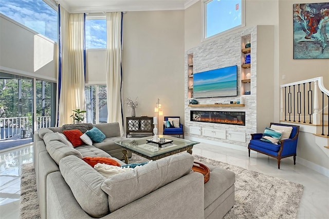 living room with a stone fireplace, a wealth of natural light, and a high ceiling