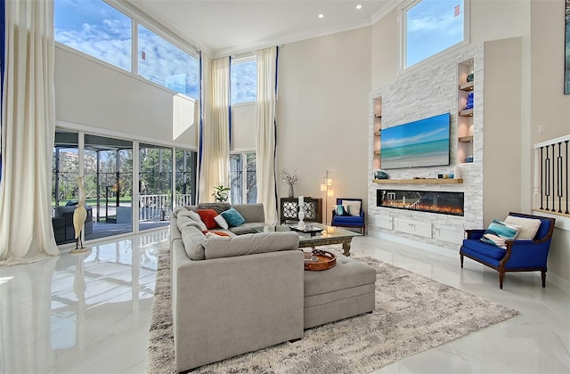 living room with plenty of natural light, crown molding, a fireplace, and a high ceiling