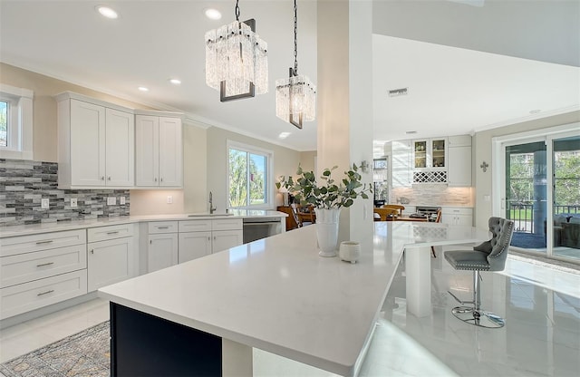 kitchen with a chandelier, white cabinets, stainless steel dishwasher, and sink