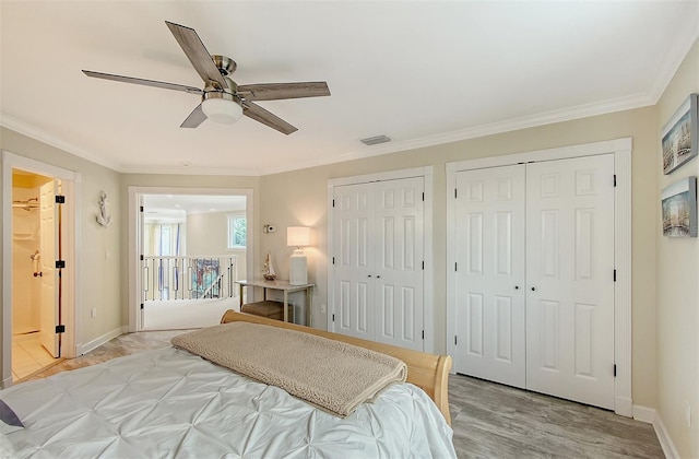 bedroom with multiple closets, ceiling fan, crown molding, and light wood-type flooring