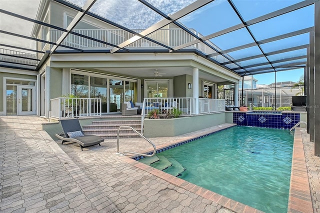 view of swimming pool featuring glass enclosure, pool water feature, ceiling fan, and a patio