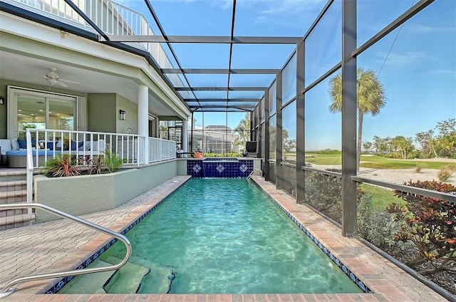 view of pool featuring glass enclosure, ceiling fan, and pool water feature