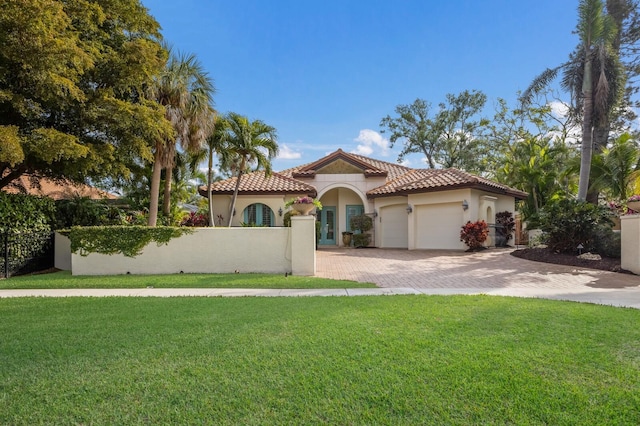 4946 Brywill Cir, Sarasota, FL 34234 - mediterranean / spanish-style home with stucco siding, a garage, a fenced front yard, a tile roof, and driveway