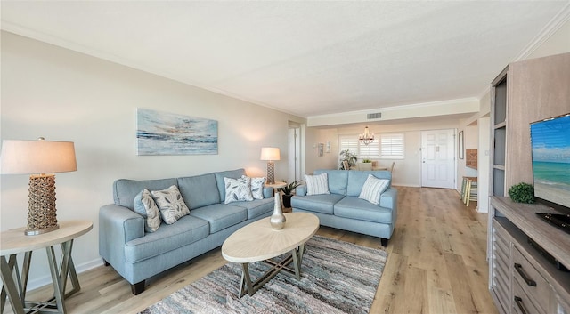 living room featuring a notable chandelier, ornamental molding, and light hardwood / wood-style flooring