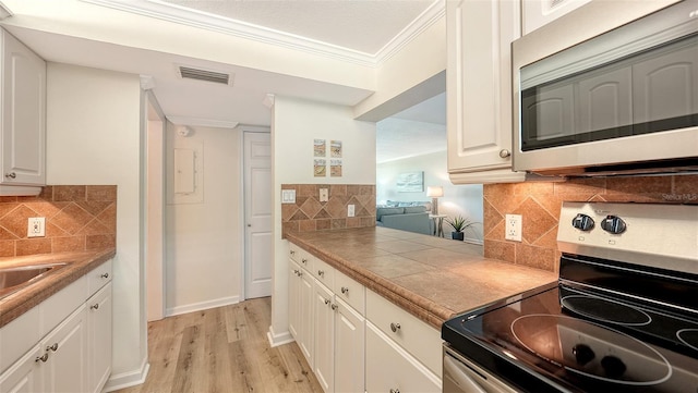 kitchen featuring decorative backsplash, white cabinetry, and appliances with stainless steel finishes