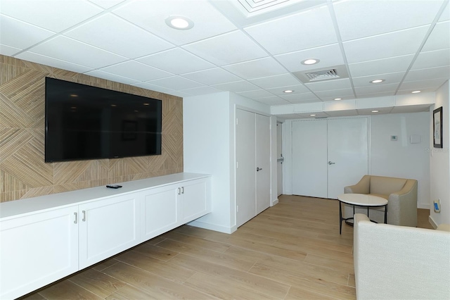 unfurnished living room with a drop ceiling and light hardwood / wood-style floors