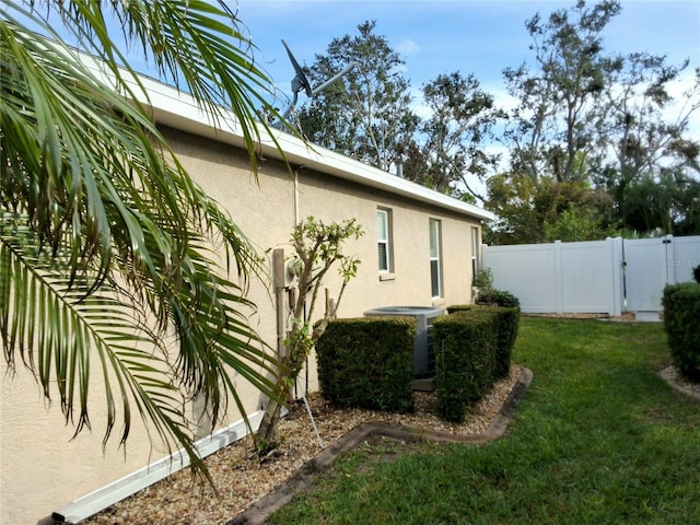 5115 44th St W, Bradenton, FL 34210 - view of home's exterior with central AC unit, a yard, fence, stucco siding, and a gate