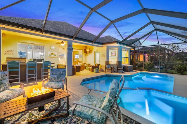 view of pool featuring an outdoor bar, ceiling fan, a lanai, an outdoor living space with a fire pit, and a patio area