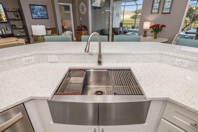 interior details with white cabinetry, light stone counters, and sink