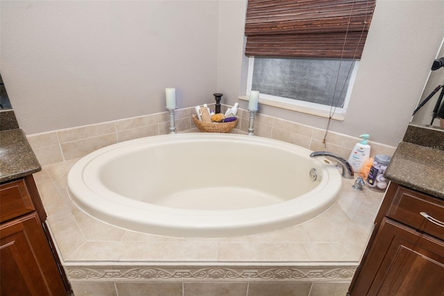 bathroom featuring tiled tub and vanity