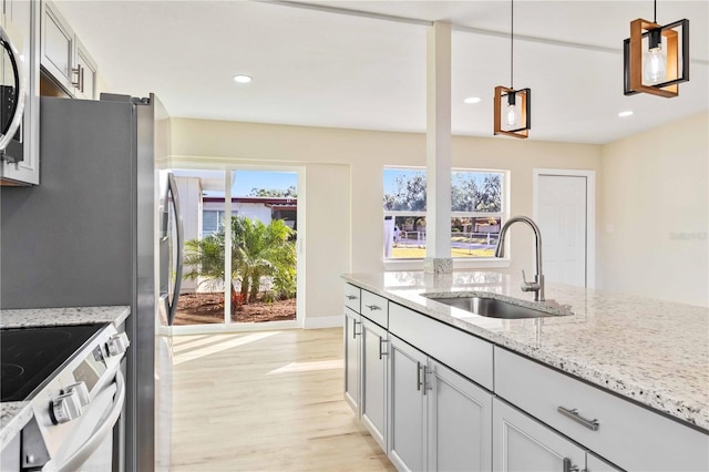 kitchen with pendant lighting, white electric range, light stone countertops, and sink