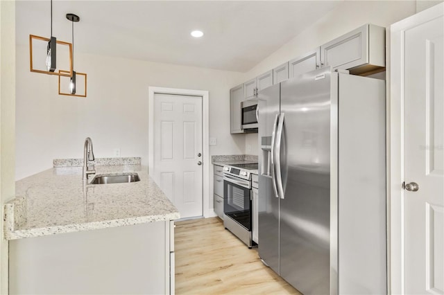 kitchen featuring pendant lighting, sink, light hardwood / wood-style flooring, appliances with stainless steel finishes, and light stone counters