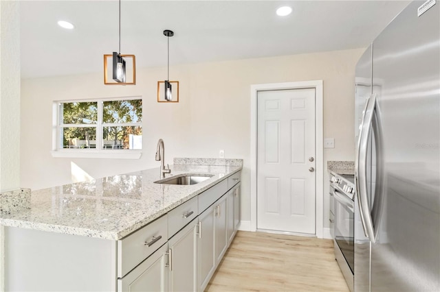 kitchen featuring sink, hanging light fixtures, light stone countertops, appliances with stainless steel finishes, and kitchen peninsula