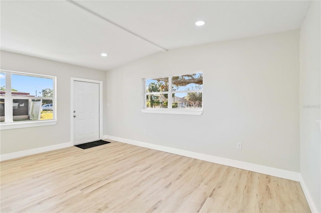 unfurnished room featuring vaulted ceiling and light hardwood / wood-style flooring