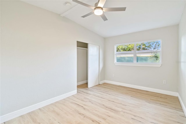 unfurnished bedroom featuring a closet, light hardwood / wood-style flooring, vaulted ceiling, and ceiling fan