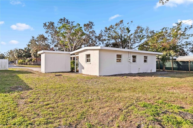 rear view of house featuring an outbuilding and a yard