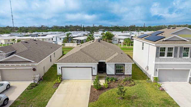 view of front of property with a garage, a front yard, and solar panels