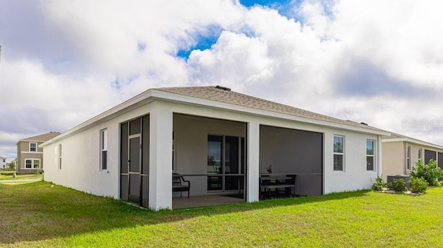 back of property with a sunroom and a lawn