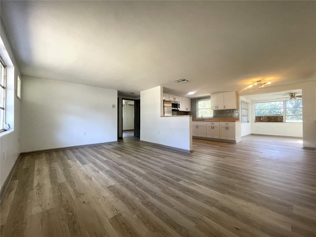 unfurnished living room with hardwood / wood-style flooring, ceiling fan, and sink