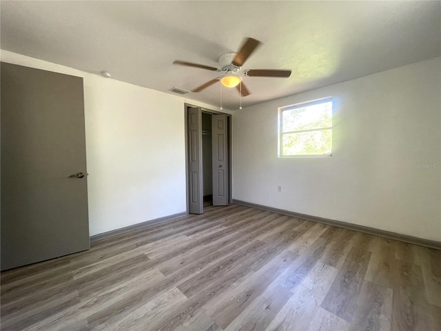 unfurnished bedroom featuring ceiling fan, light wood-type flooring, and a closet