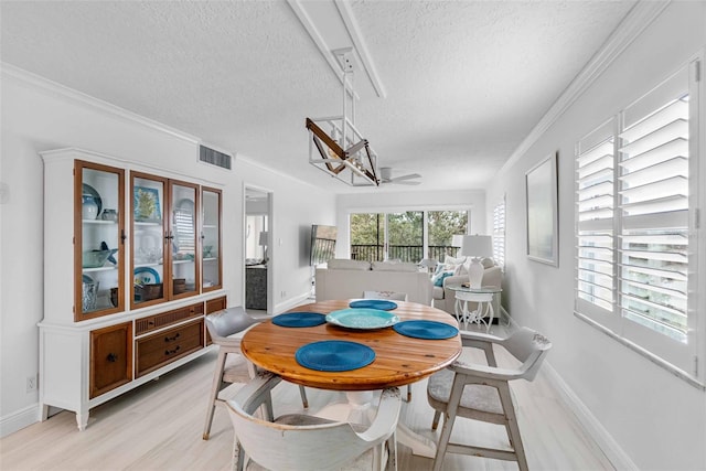 dining area featuring a textured ceiling, light hardwood / wood-style floors, ceiling fan, and crown molding