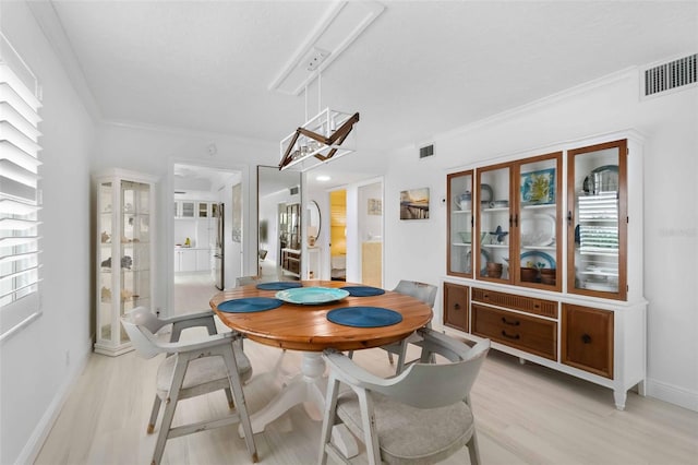 dining space with crown molding, a healthy amount of sunlight, and light wood-type flooring