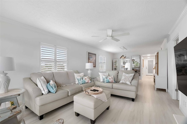 living room featuring ornamental molding, a textured ceiling, and ceiling fan