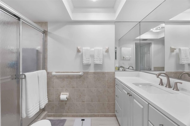 bathroom with crown molding, a shower with door, tile walls, vanity, and a raised ceiling