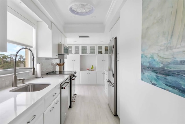 kitchen with sink, crown molding, stainless steel appliances, decorative backsplash, and white cabinets