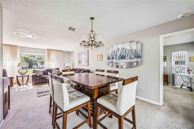 carpeted dining space with a notable chandelier and a textured ceiling