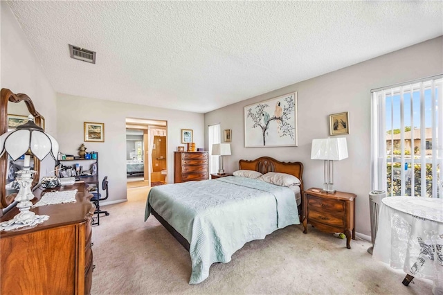 carpeted bedroom featuring ensuite bath and a textured ceiling