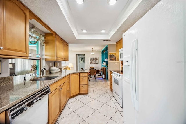 kitchen with white appliances, sink, a tray ceiling, decorative light fixtures, and kitchen peninsula