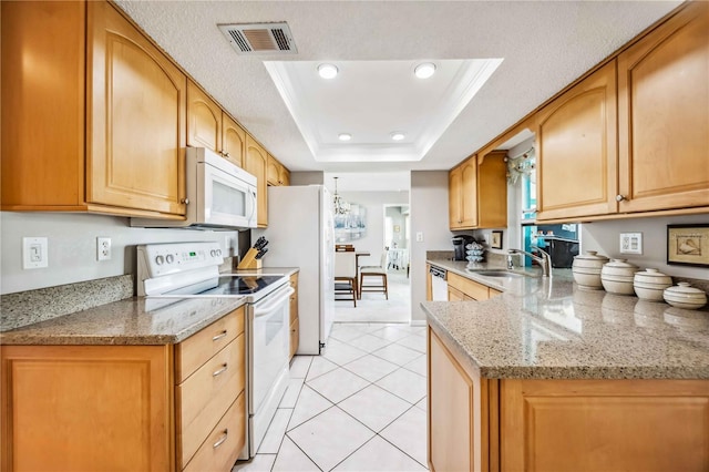 kitchen with white appliances, sink, light stone countertops, light tile patterned floors, and a tray ceiling