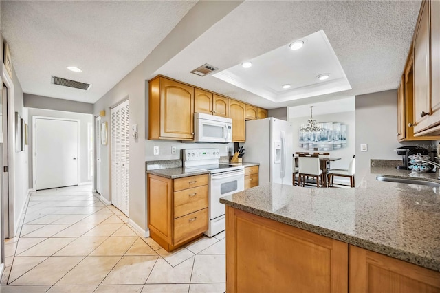 kitchen featuring white appliances, a raised ceiling, sink, light tile patterned floors, and kitchen peninsula