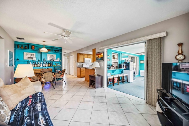 tiled living room with ceiling fan and a textured ceiling