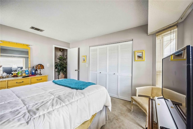 carpeted bedroom featuring a textured ceiling and a closet